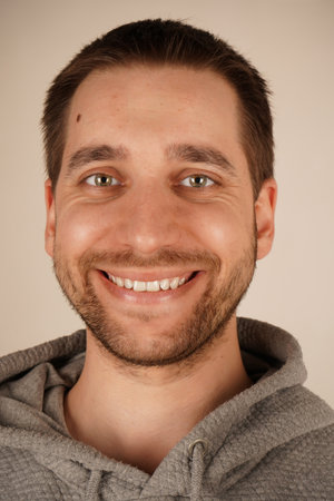 A close-up of the face of a man with dark hair and a light beard. His smiling face adds a sense of intimacy. The image emphasizes detail and natural charm.の写真素材