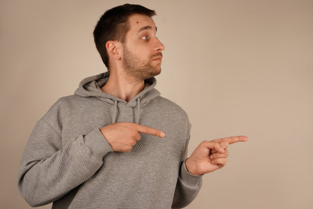 With both index fingers pointing in the same direction, the man highlights a focal point. His determined expression reinforces the purposeful gesture. The scene communicates clarity and intent.の写真素材