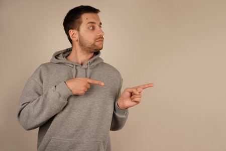 His determined expression reinforces the purposeful gesture. The scene communicates clarity and intent. With both index fingers pointing in the same direction, the man highlights a focal point.の写真素材