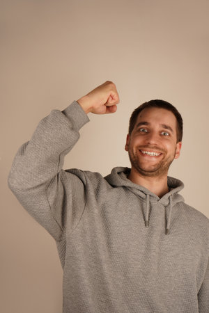 The man, with a wide grin, lifts his fists in celebration, expressing immense joy. This victorious gesture reflects a moment of success and personal achievement. Ideal for moments of triumph.の写真素材
