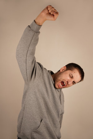 Man happy and excited with raised his hand up. Portrait of a cheerful young man holding his hand up like a winner isolated on grey background.の写真素材