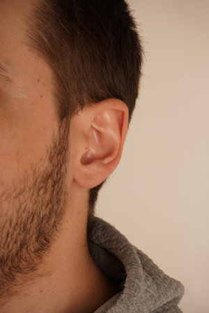 The image emphasizes simplicity and attention to detail. A minimalistic portrait highlighting the beauty of human anatomy. A close-up of a man s ear showcasing its natural lines and skin texture.の写真素材