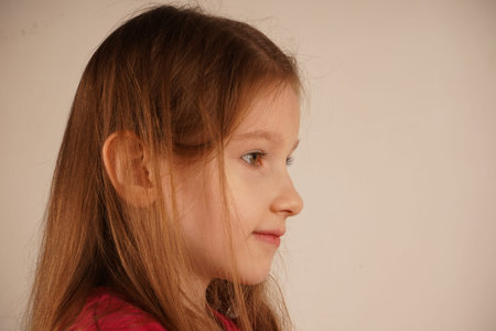 The image conveys purity and warmth. The face of a young red-haired girl with light skin is shown in a detailed close-up. Her expressive features and radiant complexion make her truly captivating.の写真素材