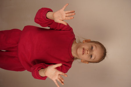 The girl raises her hands in front of her body, signaling a gesture of protection. She appears to be distancing herself from something, evoking a sense of caution and emotional space. Her posture is defensive.の写真素材