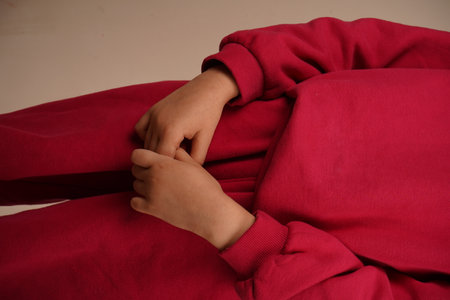 Girl in a tracksuit holding her hand together. Teenage girl in red clothes. A lighthearted glimpse of childlike innocence.の写真素材