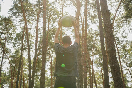 A moment of musical mindfulness in nature. A man holding a handpan above his head in a forest,...