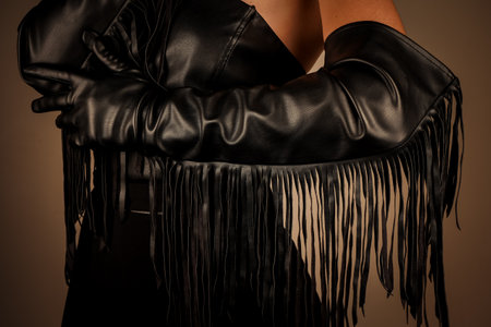 A silhouette of a woman wearing fringed leather gloves and a sophisticated outfit that exudes bold confidence. The woman holds her arm bent at the elbow, beautifully revealing her black fringe.の写真素材
