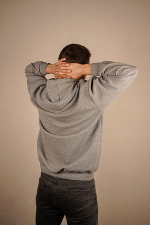 Relaxed and stretching arms and hands behind head and neck of middle aged man wearing hoodie over...