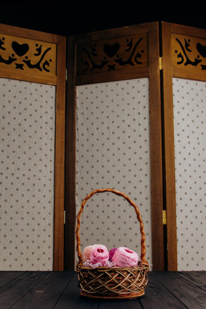 Against the background of a polka-dotted wall, a vertical photo of a brown wicker basket in which...