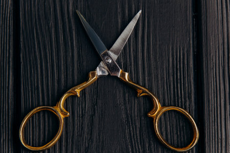 Iron scissors with golden top shot close-up on black boards. Scissors for needlework on the table.の写真素材