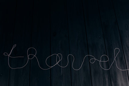 The word travel is written with threads on black wooden boards close-up. An ideal option for tourism...