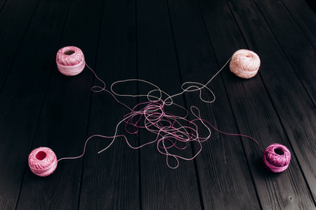 Tangled multicolored threads from four skeins lie on black wooden boards. Threads for knitting on a black background.の写真素材