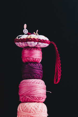 On a black background, pink and purple skeins for knitting are stacked on top of each other.の写真素材