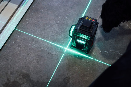 The rough surfaces of a room are illuminated by the bright glow of the green laser beams projected...