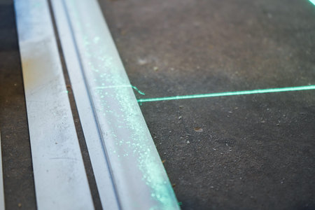 The dusty surface of the floor is illuminated by two sharp green laser lines, perfectly aligned for...