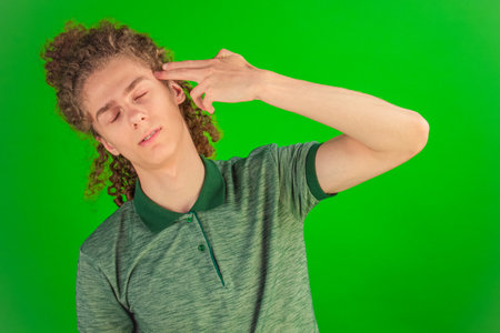 Eyes widened in shock, the man with lively curls freezes in surprise, perfectly framed by the vivid green backdrop.の写真素材