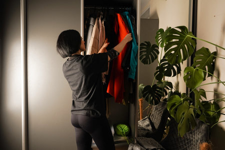 The scene reflects a calm and organized home setting. From behind, a woman in black loungewear...
