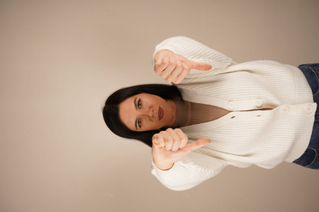 Woman showing double thumbs up gesture, expressing a positive emotion. Her focused expression...