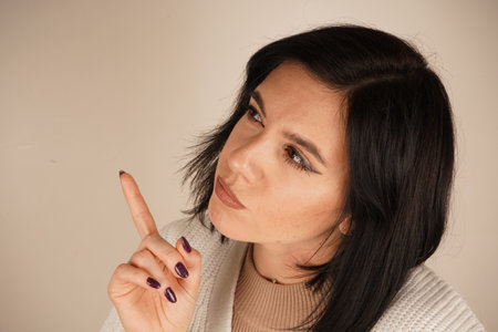 A calm pose, symbolizing mindfulness and reflection. A young woman places her hand under her chin, deep in thought. Her gaze is focused, reflecting contemplation and introspection.の写真素材