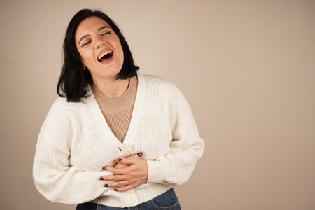 The joyful expression on her face conveys pure happiness and warmth. This gesture emphasizes her carefree and cheerful nature. A woman raises her hands, showing the backs of her fingers.の写真素材