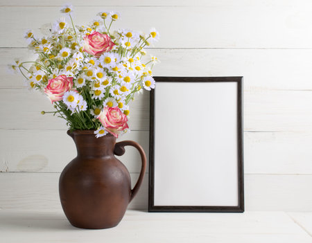 Daisy bouquet with roses in clay jug with motivational frame  for your text or picture on background of white wooden planks in scandinavian style. Home interior.の写真素材