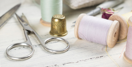 Golden thimble with set of reel of thread, scissors for sewing and needlework in Shabby Chic style. For this photo applied toning in retro style.の写真素材