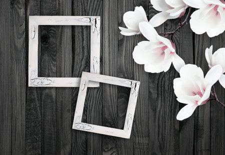 White magnolia flowers and photo frame on background of shabby wooden planks in rustic styleの写真素材
