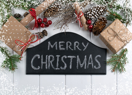 Christmas background with signboard and inscription, spruce, gift box and scroll on wooden boards.の写真素材