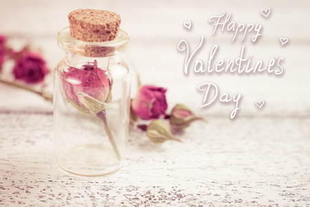 Card for Valentine Day. Small glass bottle filled with dry roses on the shabby wooden boards. Hand drawn inscription and hearts. Keeping memoryの写真素材