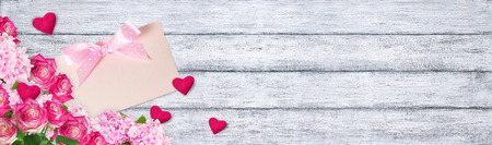 Pink roses and hydrangeas with  hearts and paper greeting card on background of shabby wooden planks. Valentine day.の写真素材
