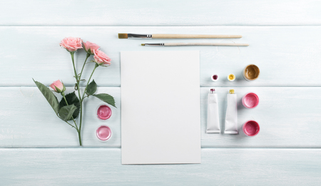 Workplace with easel, paintbrushes, roses and paints on wooden boards. Top view. Flat  design.の写真素材