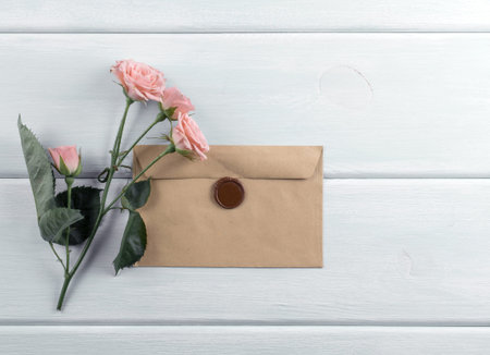 Wooden background with roses and envelope. Top view. Flat design.