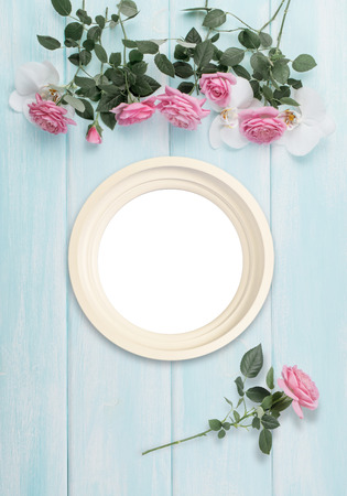 Wooden background with round frame, roses and orchid flowers and empty place for photo or text. Top view. Flat lay. Copy space.の写真素材