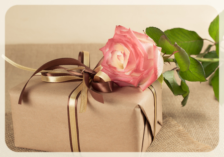 Rose and gift box with bow on sackclothの写真素材