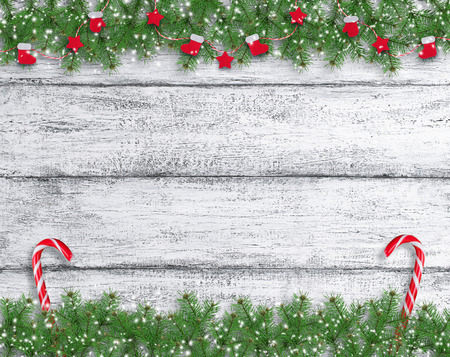 Christmas background in vintage style with Santa boot and mitten hanging on spruce branches and New Year lollipops on wooden planks in Shabby Chic style. Empty place for photo or text.の写真素材