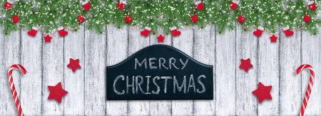 Christmas background in vintage style with Santa boot and mitten hanging on spruce branches, signboard and New Year lollipops on wooden planks in Shabby Chic style.の写真素材