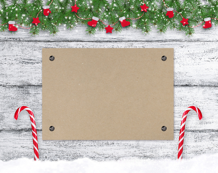 Christmas background in vintage style with c kraft eco paper, lollipops, Santa boot and mitten hanging on spruce branches. New Year holidays concept. Empty place for photo or text. Copy space.の写真素材