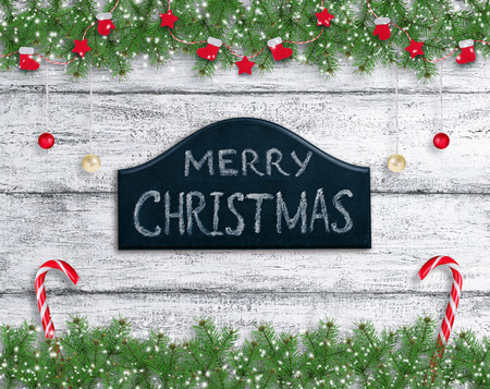 Christmas background in vintage style with balls, Santa boot and mitten hanging on spruce branches, signboard and New Year lollipops on wooden planks in Shabby Chic style.の写真素材