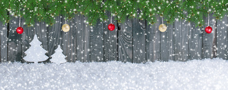 Christmas card in vintage style with spruce branches, fir trees and hanging balls on wooden wall background. New Year winter holidays concept. Empty place for text. Copy space.の写真素材