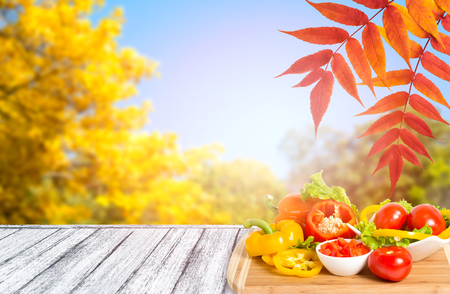 Assortment of fresh vegetables on wooden table in Shabby Chic style and autumn trees with golden leaves against the blue sky. Empty place for your decoration or advertising.の写真素材