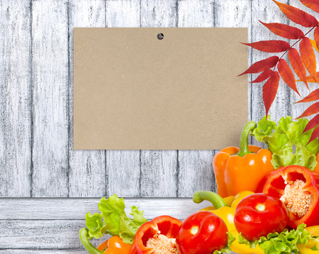 Ripe bell peppers, lettuce and tomato on wooden board and paper with place for text. Heap of various fresh bio vegetables. Healthy eating theme. Empty space for your advertising.の写真素材