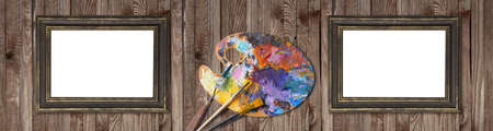 Palette for oil paints with brushes, palette knife and picture frames on shabby wooden background. Template for oil art master class advertising. Empty place for photo or text.の写真素材