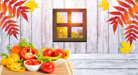 Ripe bell peppers, lettuce and tomato on wooden board and window. Heap of various fresh bio vegetables. Healthy eating theme. Empty space for your decoration or advertising. Autumn kitchen.の写真素材