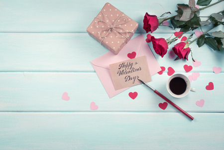 Valentine day theme. Top view of roses, hearts, packed gifts, coffee cup and envelope on shabby wooden table. の写真素材