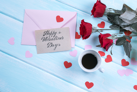 Valentine day theme. Top view of roses, hearts, coffee cup and envelope on shabby wooden table. の写真素材