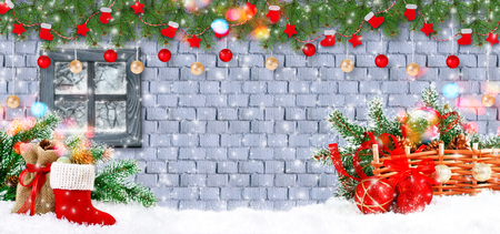 Christmas background with Santa Claus boot and bag with gifts and decorative garland with window on brick wall. New Year winter holidays concept.の写真素材