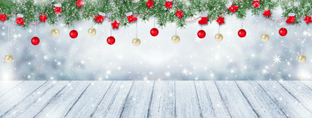 Christmas background with Santa boots, gloves, stars and balls hanging on spruce garland, wooden table and snowfall. New Year winter holidays theme. Empty place for your decoration, text, advertising.の写真素材