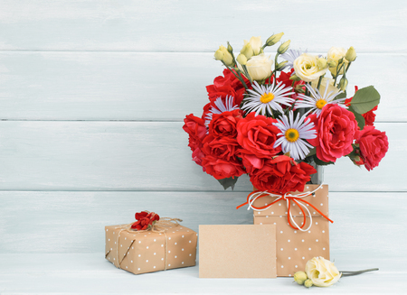 Roses and daisy bouquet, greeting card with gifts on wooden background in Shabby Chic style. Celebratory interior. Empty place for text.の写真素材