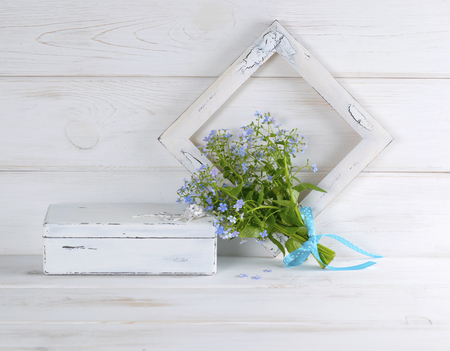 Forget-me-not flowers bouquet, vintage casket and photo frame on white wooden shabby board in provence styleの写真素材