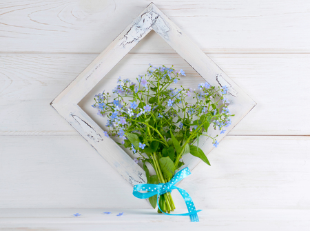 Forget-me-not flowers bouquet and vintage photo frame on white wooden shabby board in provence styleの写真素材